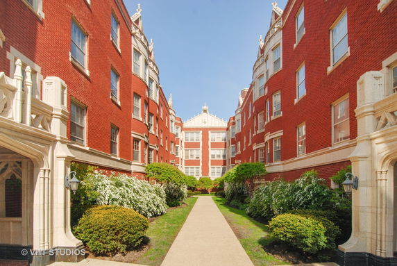 Front view of a red brick multi-story apartment building with decorative stonework.