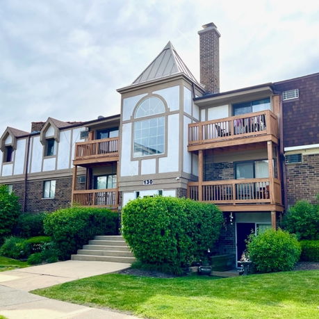 Front view of a multi-story residential building with balconies and chimney.