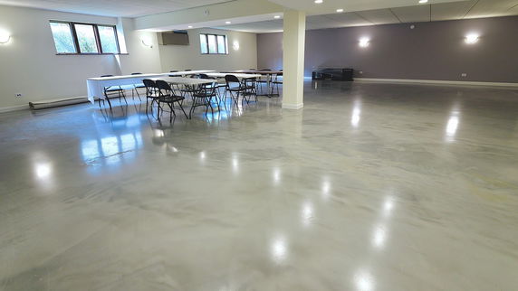 Interior view of a spacious room with polished floor and tables with chairs.