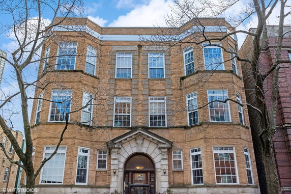 Front view of a multi-story brick building with large windows.