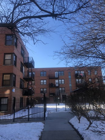 Front view of a multi-story brick apartment building with balconies.