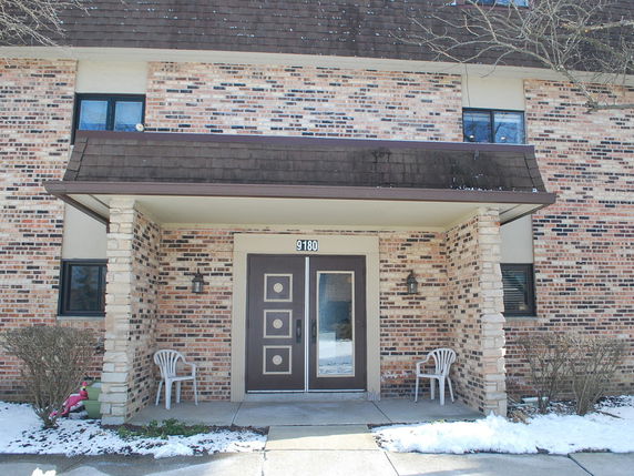 Front view of a building entrance with brick facade and double doors.