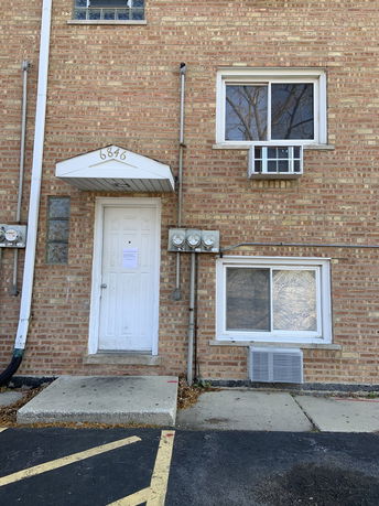 Front view of a brick building with white door and two windows.