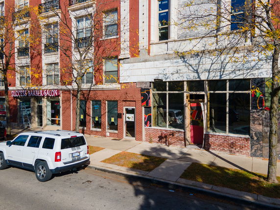 Front view of a multi-story brick building with a barber salon on the ground floor.