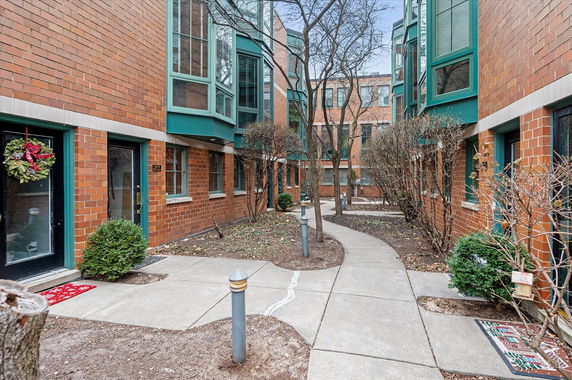 Exterior view of a brick apartment building with multiple windows and paths.