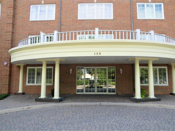 Front view of a brick building with white pillars and glass entrance doors.