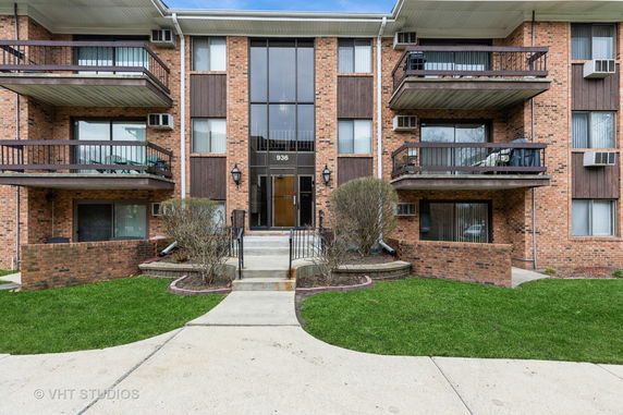 Front view of a multi-story brick apartment building with balconies.