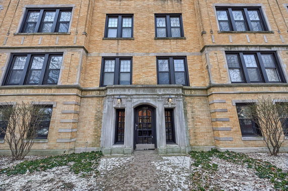 Front view of a brick apartment building with a decorative entrance.