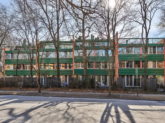 Front view of a multi-story residential building with a green facade.