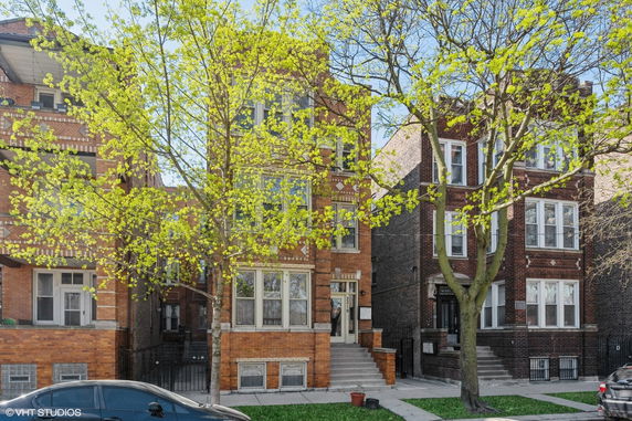 Front view of a three-story brick building with large windows and a stairway entrance.