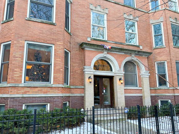 Front view of a multi-story brick building with large windows and an arched entrance.
