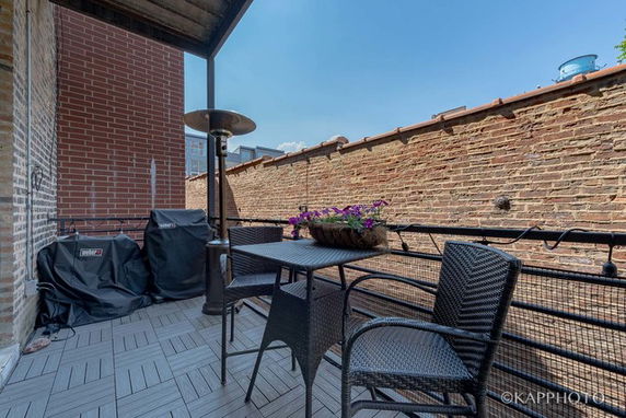 Outdoor rooftop area with seating and a grill.