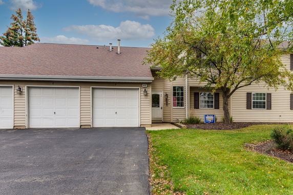 Front view of a house with a three-car garage and a tree.