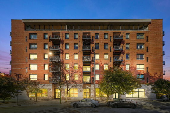 Front view of a multi-story brick apartment building with balconies and large windows.