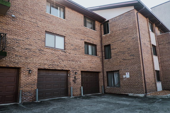 Front view of a multi-story brick apartment building with garages.