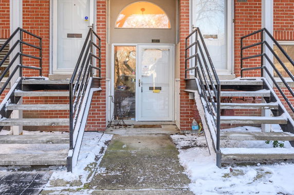 Front view of a building entrance with brick exterior and snow-covered steps.