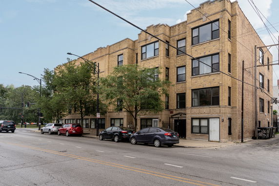 Front view of a multi-story brick apartment building on a city street.