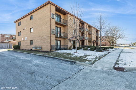 Front view of a three-story brick apartment building with balconies.