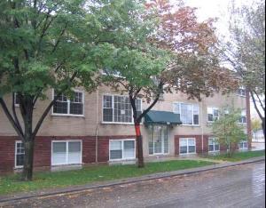 Front view of a multi-story residential building with large windows and a green awning.