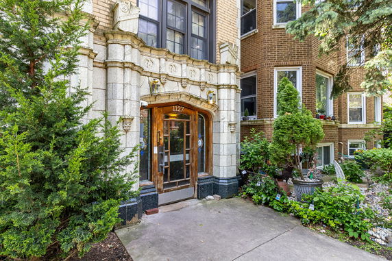 Front view of a multi-story building with ornate stone detailing and a wooden door.