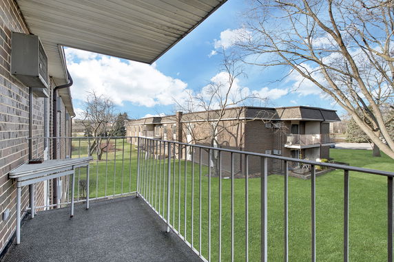 View from a balcony overlooking adjacent residential buildings and green lawn.