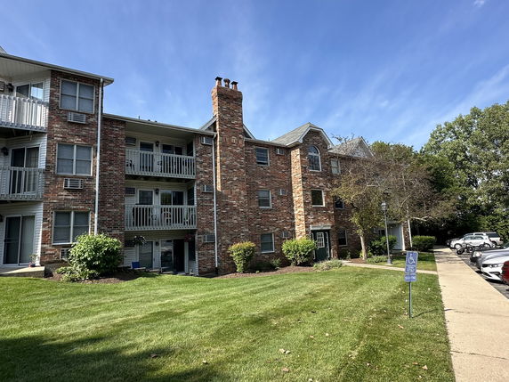 Front view of a multi-story brick apartment building with balconies.
