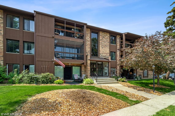 Front view of a multi-story residential building with brick and wood paneling.