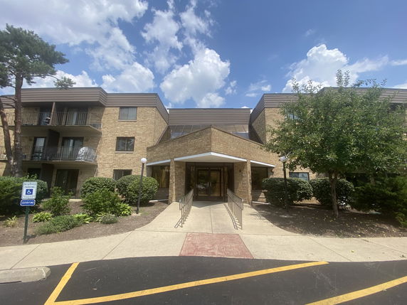 Front view of a multi-story brick building with entrance ramp and balconies.