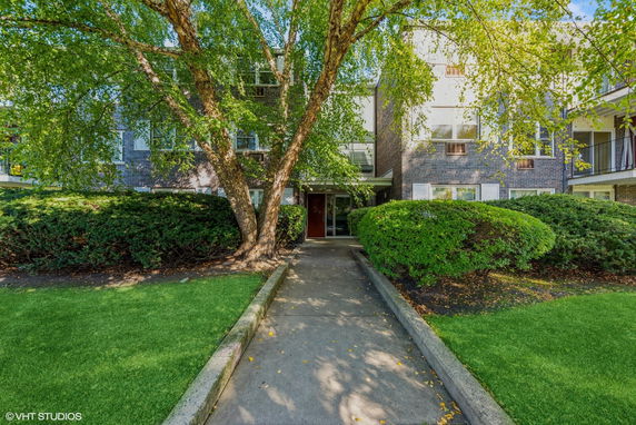 Front view of a multi-story residential building with a pathway leading to the entrance.