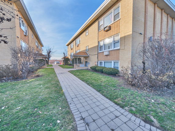 Front view of two brick apartment buildings with a walkway in between.