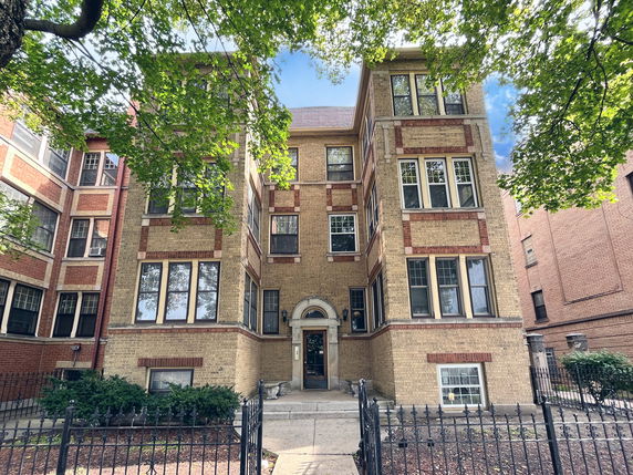 Front view of a multi-story brick apartment building with large windows.