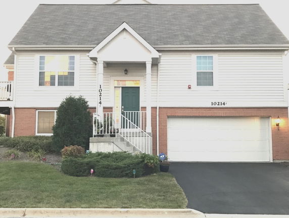 Front view of a house with a two-car garage and a sloped roof.