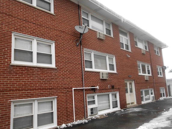 Front view of a multi-story brick building with multiple windows and satellite dish.
