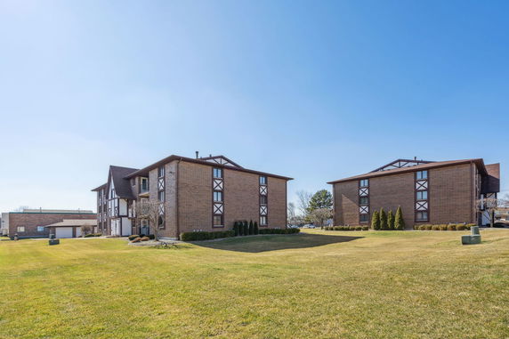 Front view of two two-story brick apartment buildings with brown and white accents.