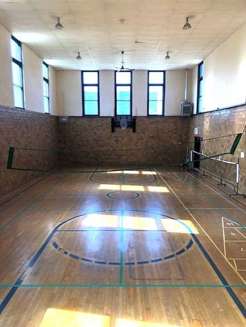 Indoor sports court with basketball hoop and badminton net.
