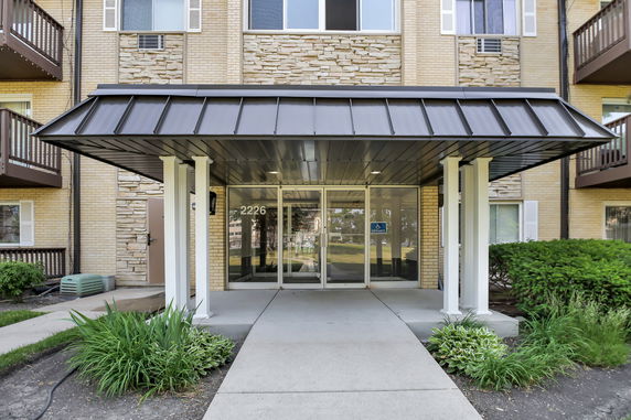 Front view of a building entrance with a covered walkway and glass doors.