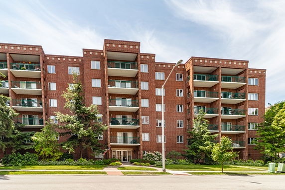 Front view of a multi-story brick apartment building with balconies.
