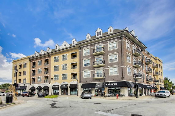 Front view of a multi-story commercial and residential building with balconies and shops on the ground floor.
