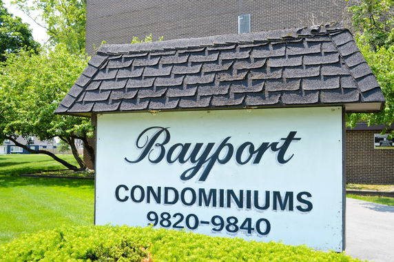 Front view of a condominium entrance sign with brick building behind.