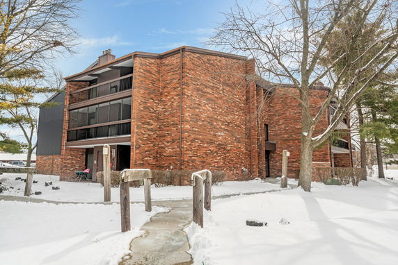 Front view of a multi-story brick building with balconies in a snowy setting.
