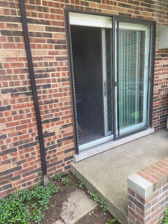 Exterior view of a building with a sliding glass door and brick wall.