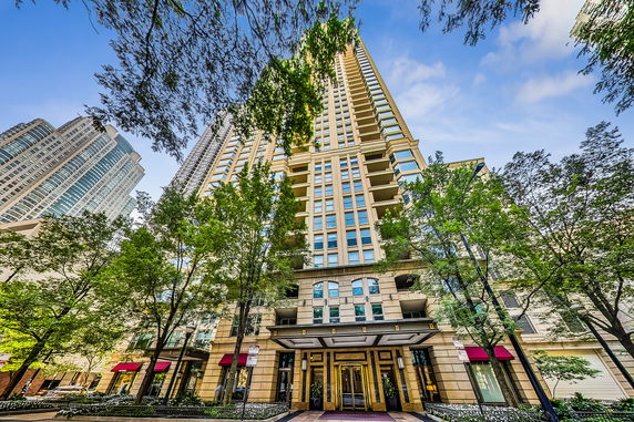 Front view of a tall residential building with multiple balconies and large windows.