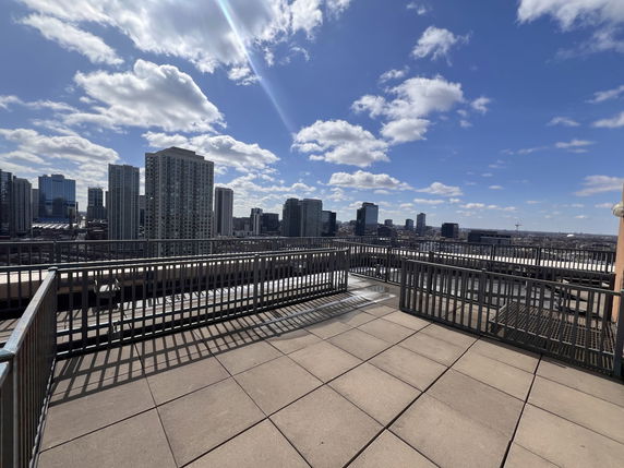 Rooftop with railings and city skyline in the background on a sunny day.