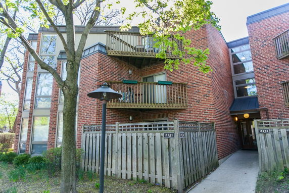 Front view of a brick apartment building with balconies and large windows.