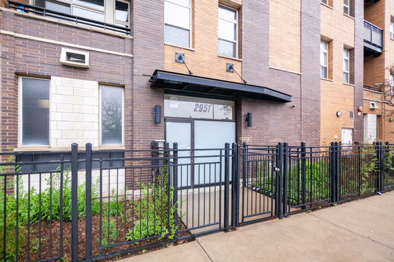 Front view of a multistory brick building with a gated entrance.