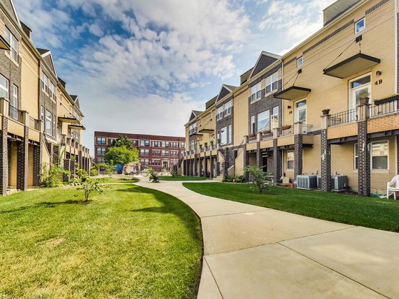 Front view of a multi-story row house with a brick exterior and a grassy yard.