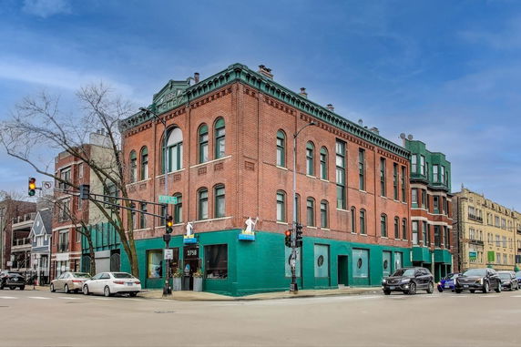Front view of a three-story brick building on a street corner.