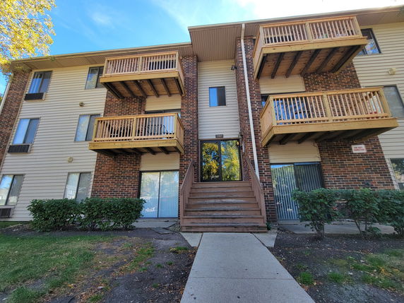 Front view of a multi-story apartment building with wooden balconies.