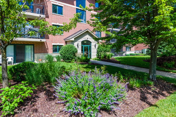 Front view of a brick building with balconies and landscaped garden.