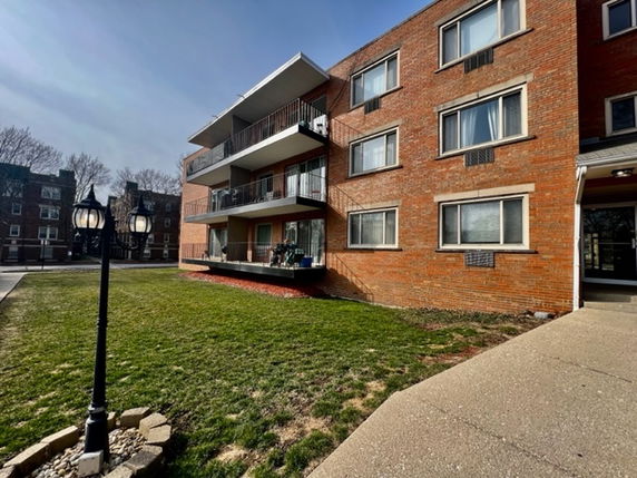 Front view of a multi-story brick apartment building with balconies.